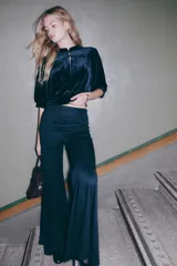 Top corto de velour negro, con cuello mao y botones forrados. Presenta canesú fruncido en la parte delantera y trasera, mangas abullonadas al codo y ribete fino en puños y bajo.