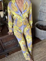Pijama de seda estampado, compuesto por una camisa de manga larga con cuello solapa, botones frontales y bolsillo ojal, y un pantalón largo recto con elástico en la cintura.