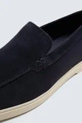 Mocasín casual de hombre, color azul marino, con parte superior de serraje (gamuza) y suela de goma a contraste color beige. Presenta un detalle de bordón cosido en la pala.