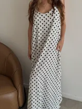 Vestido largo de crepe con estampado de lunares negros sobre fondo blanco. Presenta un diseño de corte holgado con breteles finos y escote redondeado.