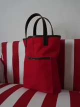 Bolso matero de lona color azul con detalles en cuero marrón, con asas cortas y logo de la marca en cuero.