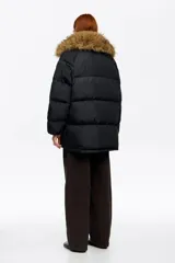 Campera tipo plumífero de largo medio y corte recto en tejido técnico, con cierre frontal, capucha con borde de pelo sintético desmontable y bolsillos frontales con solapa.