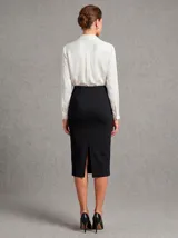 Falda recta de corte clásico, color negro, con cintura alta, pinzas delanteras y costura central vertical. Presenta un tajo en el ruedo trasero.