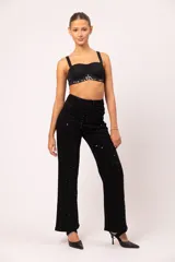 Pantalón de jean negro de tiro alto y corte wide leg, con apliques de strass negros en la parte frontal.