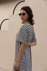 Vestido largo a rayas horizontales grises y negras, con cuello bote, mangas cortas y aberturas laterales. Incluye lazo en la cintura.