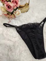 Conjunto de lencería compuesto por un top de cuello alto y una tanga, confeccionados en terciopelo negro con detalles de encaje y microtul. El top presenta mangas cortas con terminaciones en encaje y el borde inferior decorado con una cinta y encaje. La tanga es regulable y combina la textura del terciopelo con bordes de encaje.