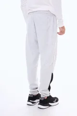 Pantalon de jogging de felpa en color gris melange, con cintura elástica ajustable mediante cordones, puños en los tobillos y paneles laterales en contraste de color negro en la parte inferior de las piernas.