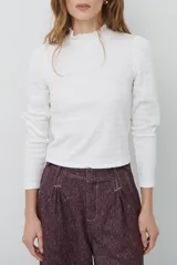 Polera de manga larga con cuello alto y detalle de volados en el borde. Confeccionada en tejido acanalado de textura suave y ajuste al cuerpo.