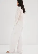 Blusa de diseño recto color crudo con diseño bordado floral, cuello camisero, manga larga con puños anchos abotonados y cierre delantero con botones.