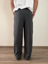 Pantalón de vestir de corte baggy, color gris oscuro, con pinzas frontales y bolsillos laterales.
