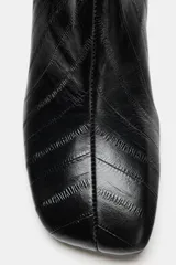 Botín de piel de color negro con textura efecto animal print, tacón fino y punta cuadrada.