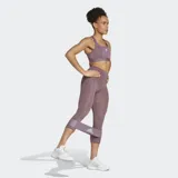 Sujetador deportivo Adidas de sujeción media, color morado, con escote cuadrado y tirantes cruzados en la espalda. Presenta paneles de malla elástica en zonas de calor y tecnología AEROREADY.