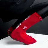 Medias deportivas de caña media en color rojo, con diseño antideslizante en la planta del pie y detalles de la marca en blanco.