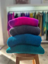 Buzo de tejido de punto en lana merino, con diseño oversize, manga ranglan y cuello levemente elevado. Presenta una textura de punto grueso y se destaca por sus colores vibrantes.