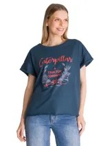 Remera de corte relajado color azul, con cuello redondo y mangas cortas con dobladillo. Presenta un estampado gráfico frontal con la inscripción Caterpillar A Tractor Company en tonos rojos y detalles botánicos.