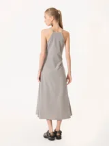 Vestido largo de punto gris con brillo, corte al cuerpo en la parte superior con breteles finos y espalda tipo halter, y falda evasé.