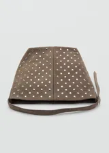 Bolso tipo hobo de cuero gamuzado color marrón, con diseño de tachas metálicas plateadas distribuidas por toda la superficie. Cuenta con una correa de hombro integrada y cierre superior.