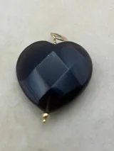 Dije de corazón grande de piedra facetada en colores negro, violeta y naranja, con engarce dorado.