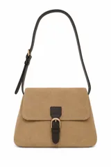 Cartera tipo bandolera de gamuza en color tostado, con solapa frontal y detalle de tira de cuero sintético marrón oscuro con hebilla metálica dorada. Cuenta con una correa ajustable y hombrera del mismo material oscuro.