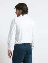 Camisa de manga larga con estampado de rayas verticales finas en color azul y blanco. Presenta cuello button-down, cierre frontal con botones nacarados y un bolsillo en el pecho.