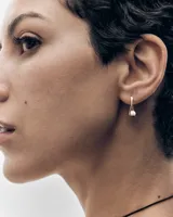 Aros dorados con diseño cruzado y una perla colgante, de la marca PDPAOLA.