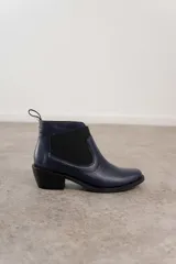 Botín negro de cuero con elásticos laterales, taco bajo y tirador trasero.