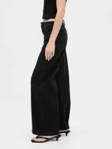 Jean de corte wide leg en color negro, con tiro alto y cierre frontal con botón y cremallera. Presenta un diseño de cinco bolsillos y trabillas para cinturón.