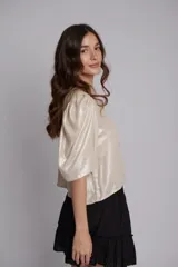 Blusa de lino con acabado metalizado brillante, de corte corto y mangas abullonadas con diseño fluido.