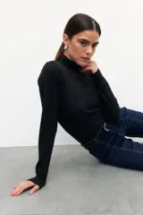 Polera negra de tejido de punto con textura acanalada, corte al cuerpo y cuello alto.