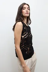 Top sin mangas confeccionado en tejido de crochet con patrón geométrico y floral, en color beige claro.