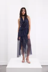 Falda midi de microtul con estampado de lunares blancos sobre fondo azul marino. Presenta un diseño de falda base corta con capas superpuestas irregulares que aportan movimiento y fluidez.