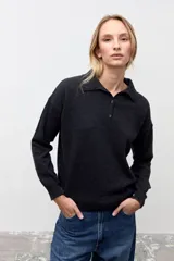 Sweater de punto color gris oscuro, con cuello polo y cierre frontal parcial con botones. Presenta mangas largas y un diseño de calce holgado.