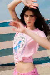 Remera rosa de algodón con estampa circular en azul con un caballo parado de manos y la leyenda "The Ranch Dress Code".