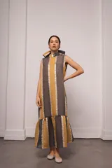 Vestido largo color ocre con estampado de cuadrados dorados, cuello alto y corte amplio. Incluye viso liso al tono.