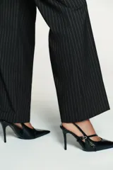 Zapato de tacón alto fino con diseño slingback, acabado en punta y textura de relieve tipo reptil. Presenta tiras laterales decorativas con hebillas metálicas doradas y tira trasera elástica para mayor ajuste.