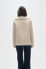 Chaqueta de eco-cuero negro con interior y cuello de piel sintética, diseño holgado, manga larga y cierre frontal con un botón.