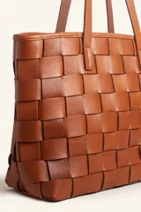 Cartera tote de cuero marrón con diseño trenzado a mano, de formato rectangular y doble asa de hombro.