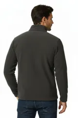 Buzo de polar color negro, con cuello alto y cierre frontal parcial.