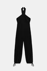 Mono largo negro con escote halter cruzado ajustable y bajo abullonado con lazada ajustable en los tobillos. Presenta un corte holgado en las piernas.