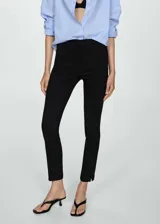 Pantalón de vestir negro, de corte ajustado y tobillero, con cierre frontal de cremallera y botón, trabillas para cinturón y bolsillos de ribete traseros.