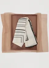 Fular cuadrado de lana con estampado geométrico de líneas negras sobre fondo color crema.