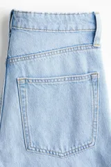 Jean wide leg de tiro alto en denim de algodón celeste claro, con diseño de cinco bolsillos, cierre de cremallera y botón metálico.