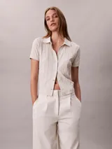 Chomba Calvin Klein de manga corta en color blanco, con cuello clásico, cierre frontal con botones y diseño de jacquard con estampado integral.