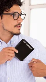 Billetera de cuero color marrón oscuro con detalle de costura artesanal en blanco. Interior con compartimentos para billetes, visor y tarjeteros.