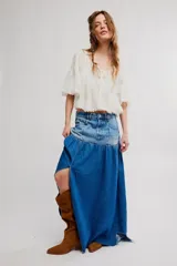 Falda maxi de denim con canesú de tiro alto y cuerpo fruncido, abertura frontal y ruedo sin terminar. Combina paneles con diferentes lavados de jean.