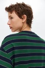 Remera de punto a rayas horizontales en color verde y azul marino, con cuello redondo, mangas largas de hombros caídos y un bolsillo de parche en el pecho.
