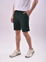 Bermuda de tejido de punto color verde oscuro, con cintura elástica y cordón ajustable, bolsillos laterales y corte recto.
