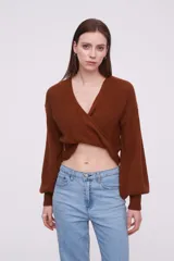 Sweater de tejido de punto color marrón, con diseño cruzado frontal, cuello en V profundo y mangas largas con puños ajustados.