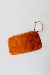 Bolso tipo hobo de gamuza color marrón, con diseño de flecos en los laterales y correa integrada al cuerpo del bolso.