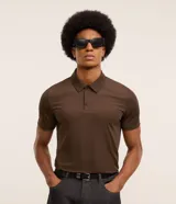 Camisa polo masculina de manga corta, confeccionada en tejido técnico de poliamida con elastano. Presenta cuello inglés con cierre de botones y diseño liso en color marrón, con tecnología de secado rápido y confort térmico.